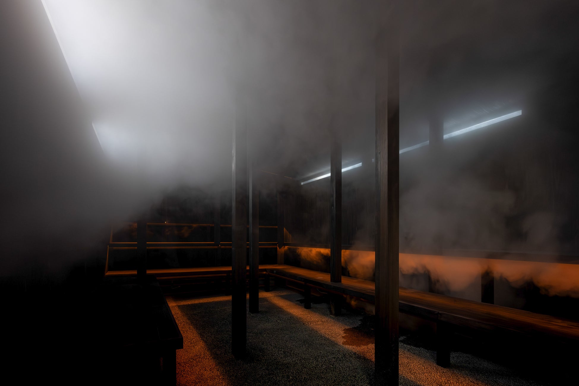 薬草スチームサウナ(男性):黒を基調としたシンプルなつくり。薬草の蒸気と壁面から差し込む太陽光、夜は最小限のライティングで幻想的な空間を演出。