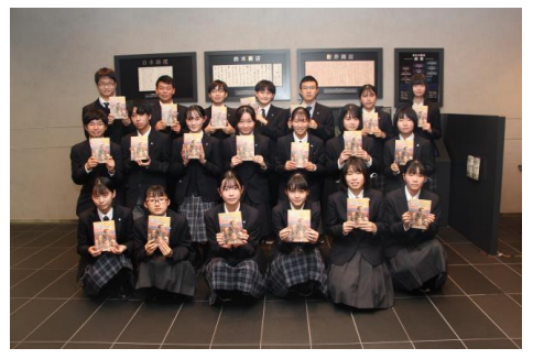 【歴史展示コーナーの前で2巻を持つ、 須磨学園高等学校の皆さん（双日本社にて）】