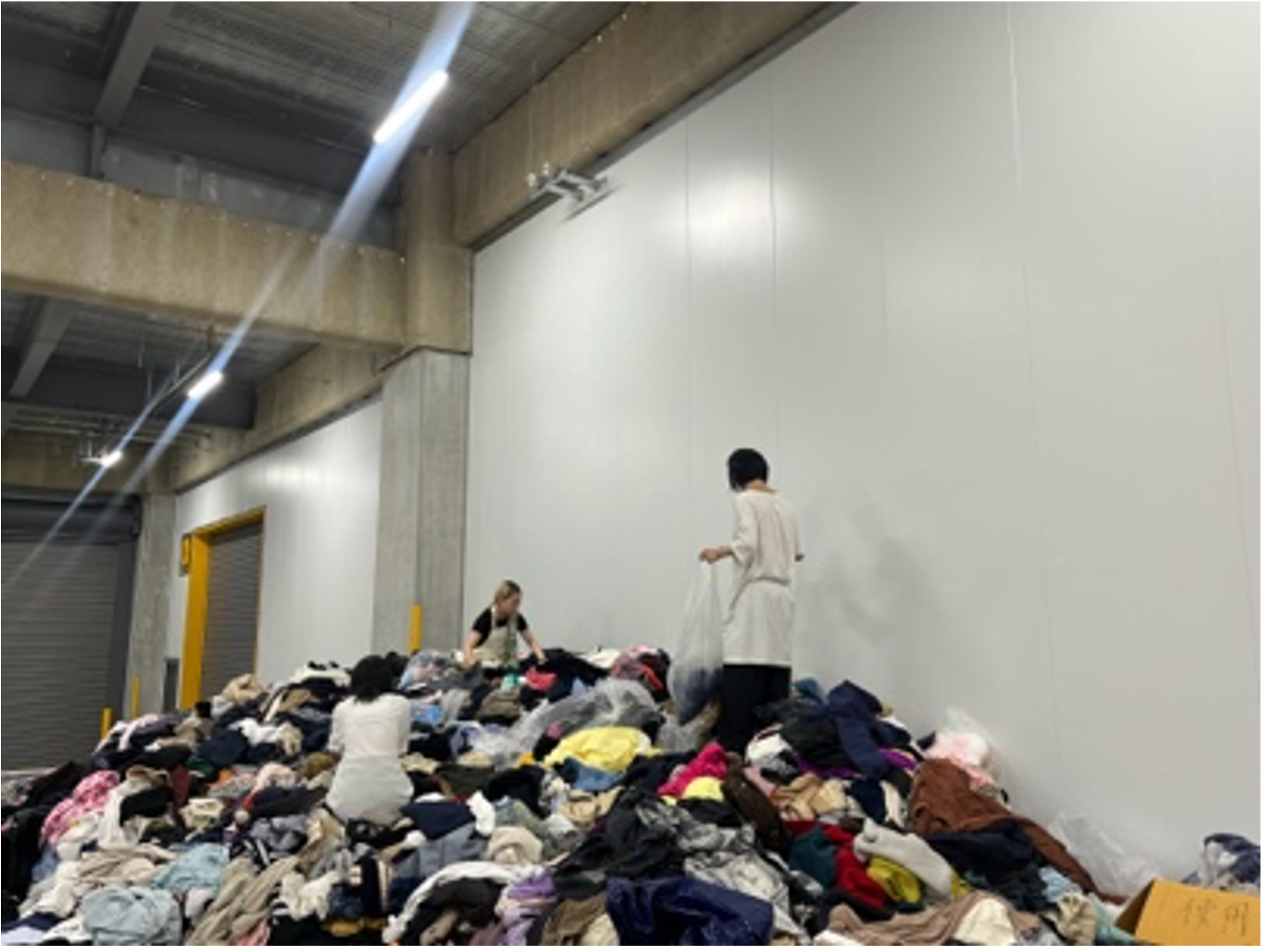 回収された洋服の山からショーピース制作用の衣装をセレクトする学生たち