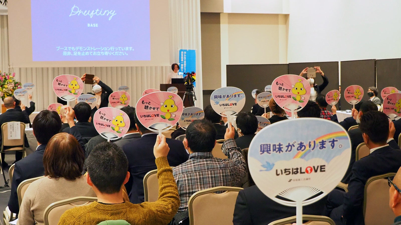 会場参加の約50人全員が審査員となり「うちわ」の表裏でプレゼンを審査した