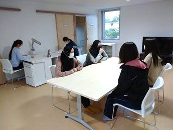 ユニット内共同スぺース。TVやテーブルの他,学習用の机を配置している