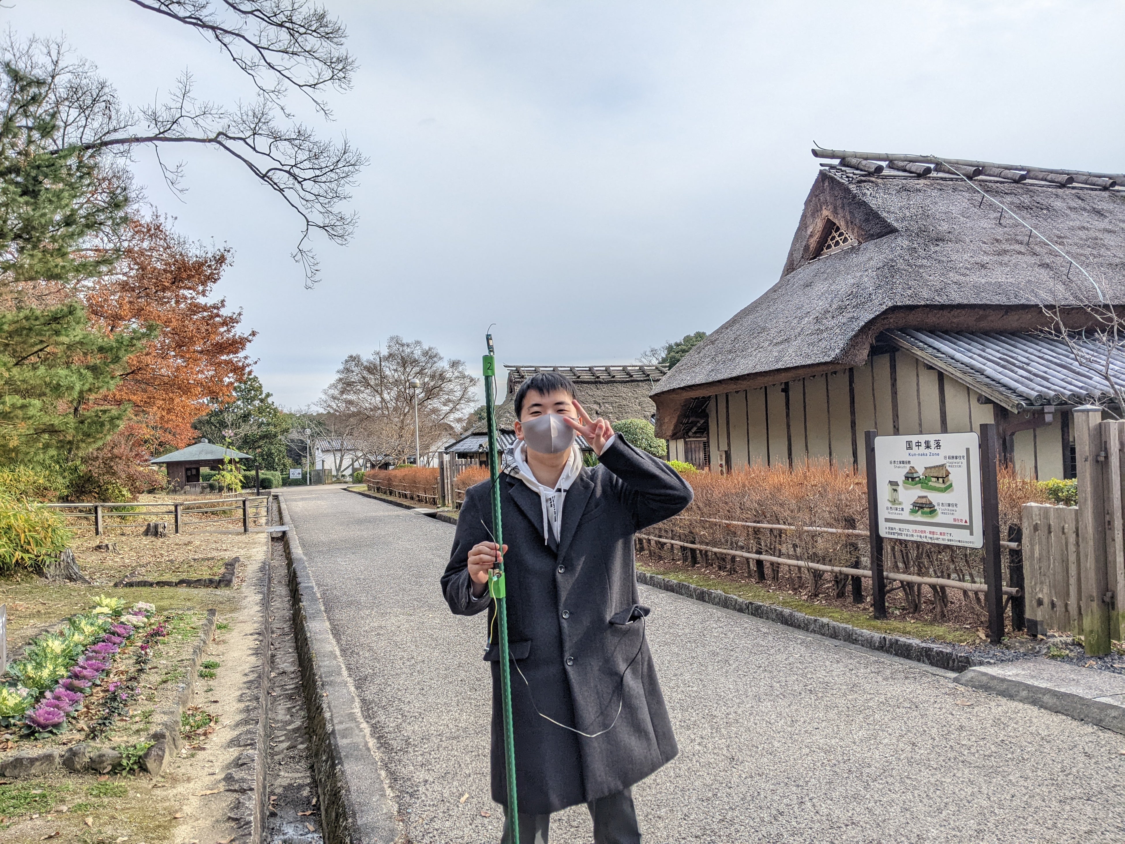 アンテナを取り付けたパイプを持って測定を行う（県立民俗博物館にて）