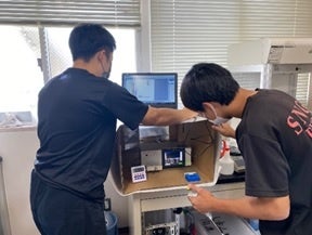 インピーダンス測定装置系と兼松研学生が取り組んでいる様子