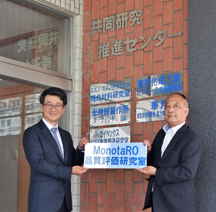 k-Team開設式にて設置する銘板を掲げる竹茂校長（右） と鈴木代表取締役社長（左