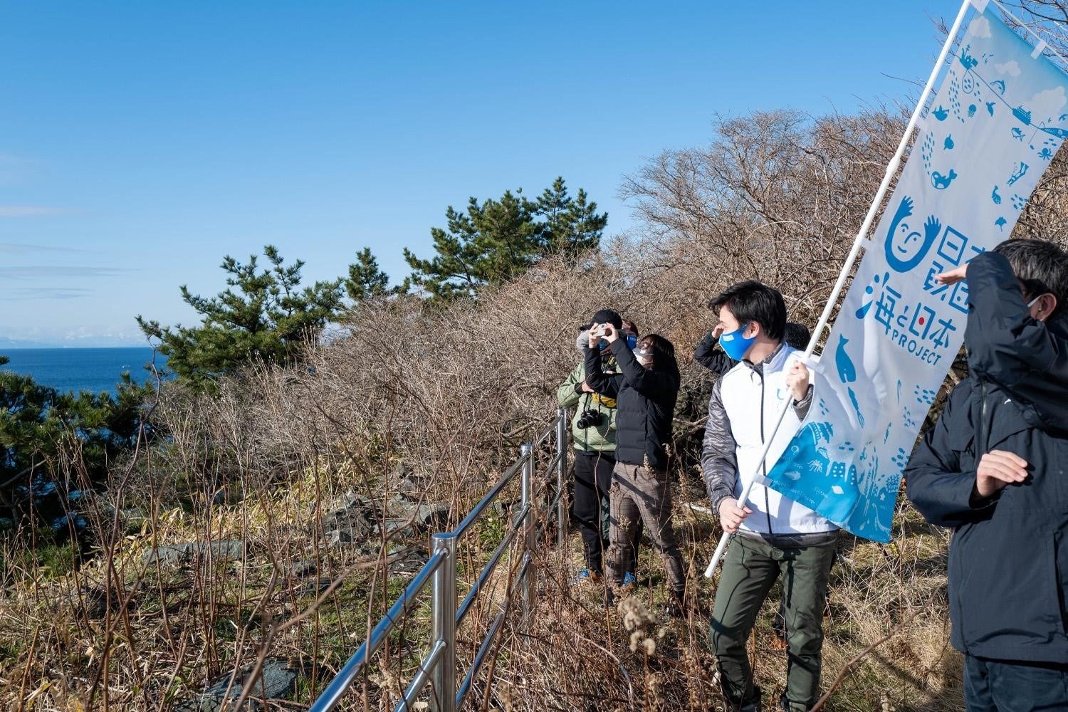 汐首岬灯台が建つ高台から津軽海峡を眺める参加者