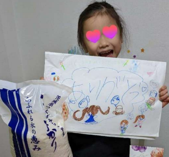 支援品のつくばみらい市産のお米を持って喜ぶ子供たち