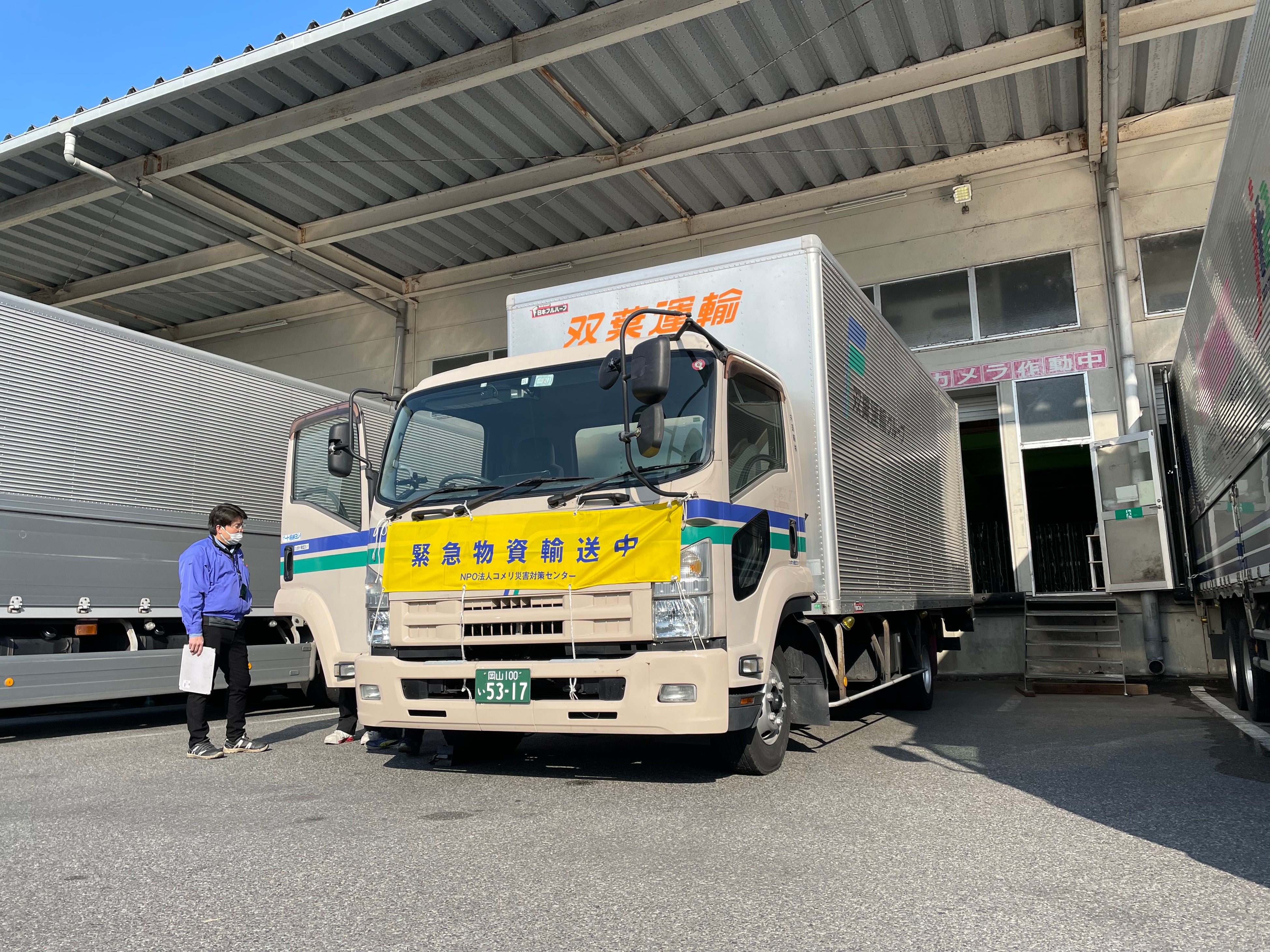 9時、コメリ岡山流通センターにて「緊急物資輸送中」横断幕をつけ出荷準備