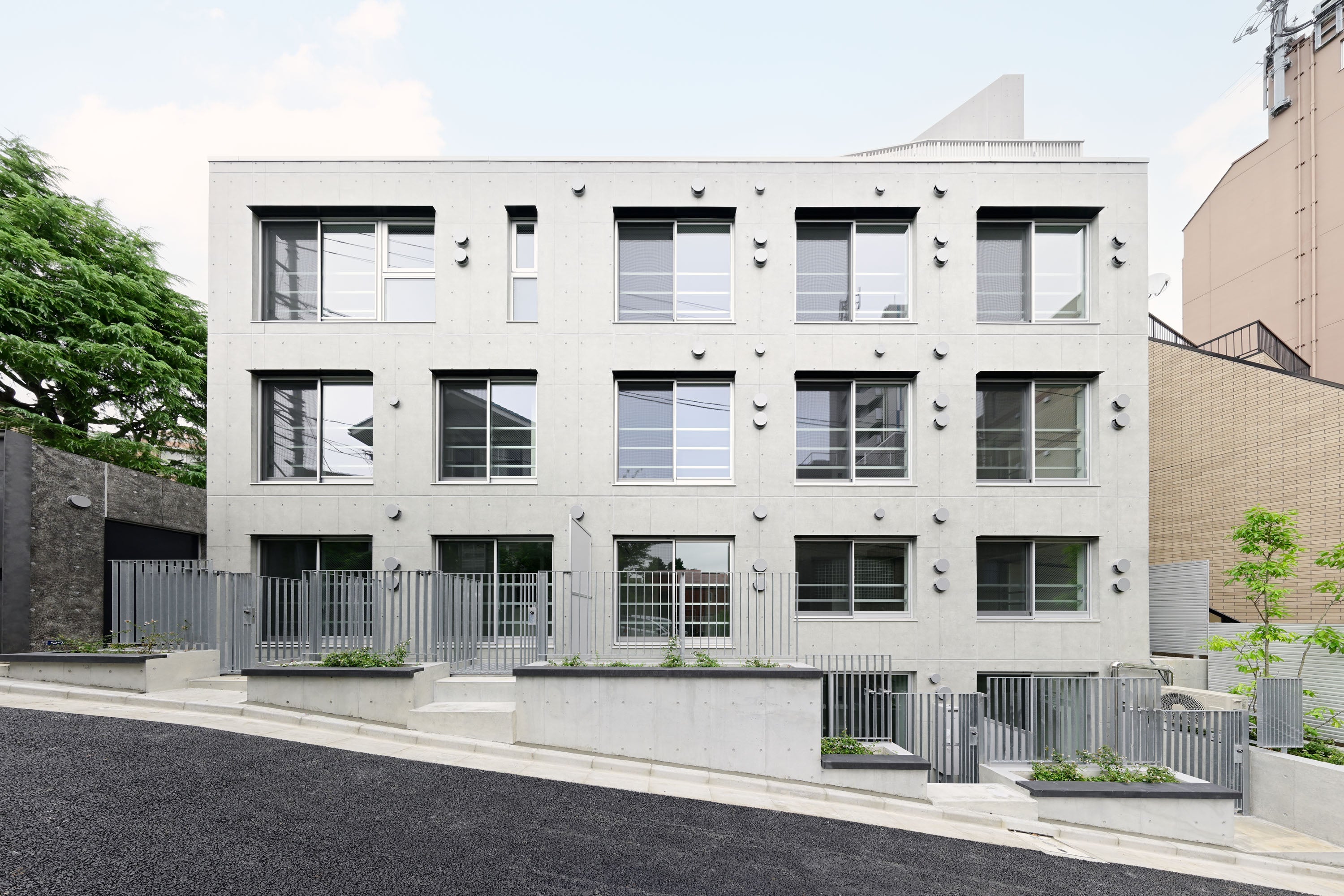 高低差のある地形を活かし、地下住戸でも採光条件の良い開放的な居住環境を実現。前面道路に面する窓の上部には黒い庇を設置。アプローチの「黒の帯」と呼応して建物の外観を印象づけます。