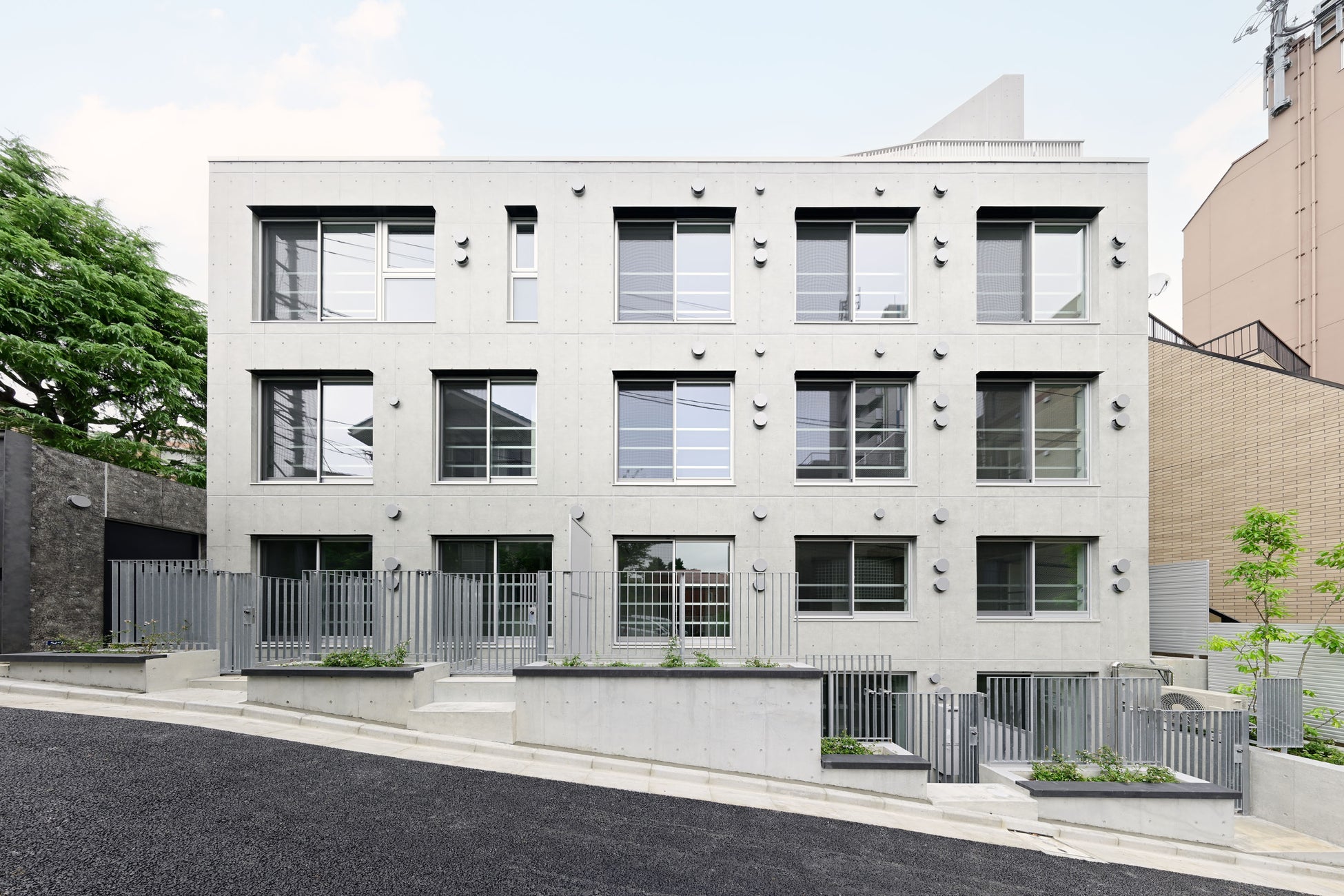 高低差のある地形を活かし、地下住戸でも採光条件の良い開放的な居住環境を実現。前面道路に面する窓の上部には黒い庇を設置。アプローチの「黒の帯」と呼応して建物の外観を印象づけます。