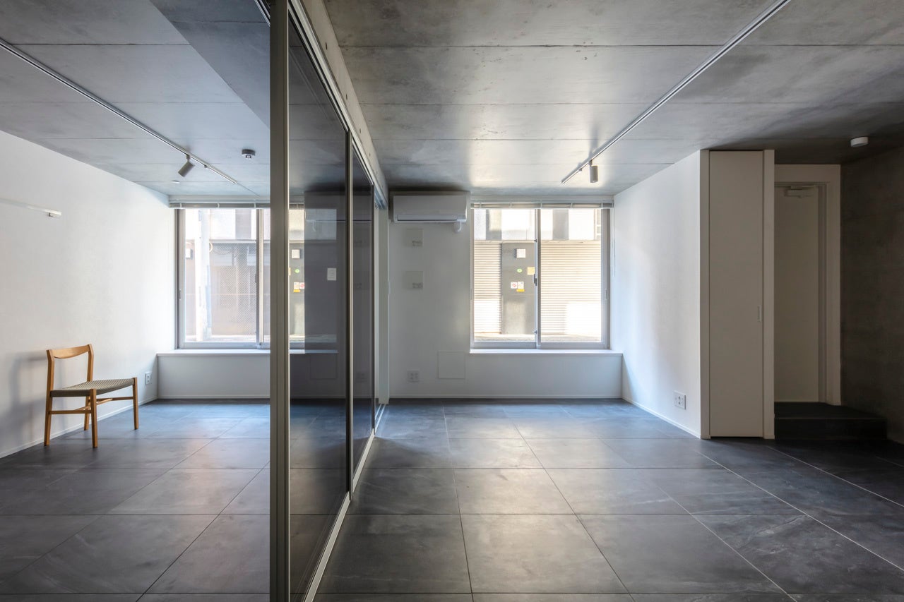 SOHO利用も想定した１階の1LDK住戸は土足でも利用しやすいタイル貼りで、ガラス引戸により一体感のある空間を創出