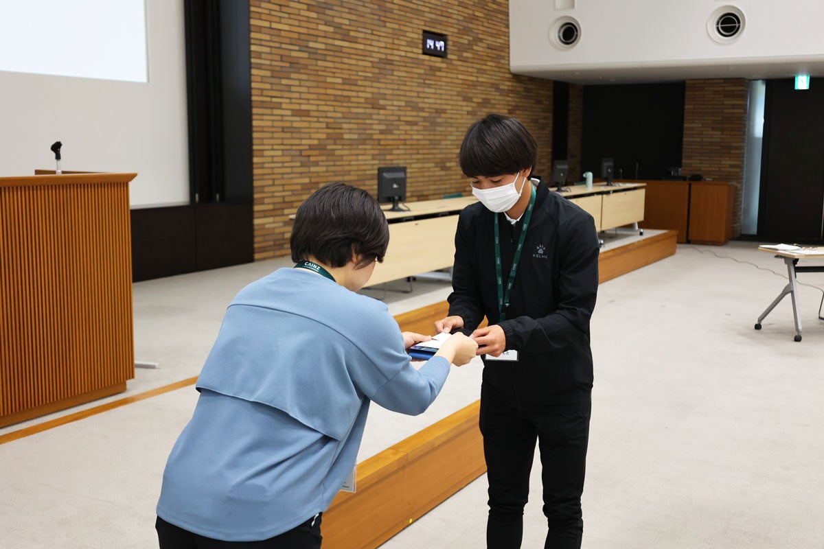 緊張した表情で名刺交換をする岩元選手