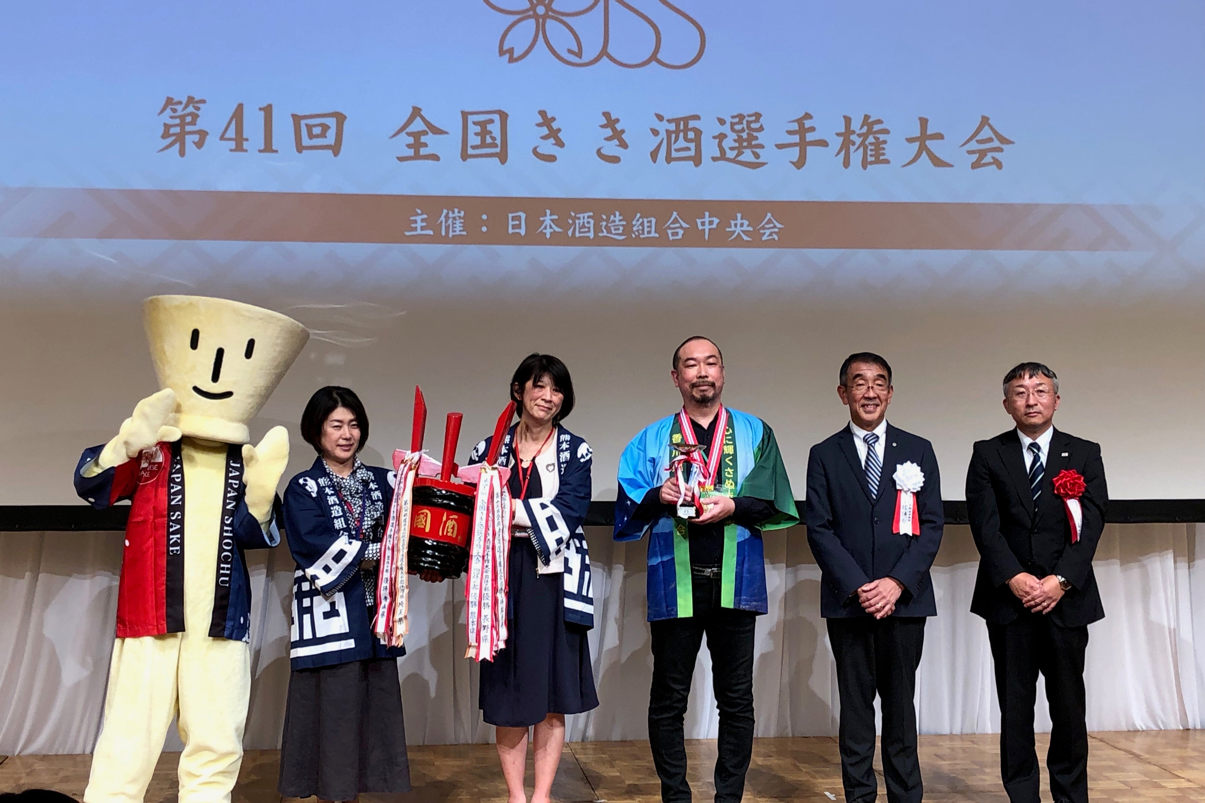 左よりおちょこくん、団体の部優勝の熊本県のペア、 個人の部優勝有村さん、中央会・佐浦副会長、協賛のJA桑原課長さん