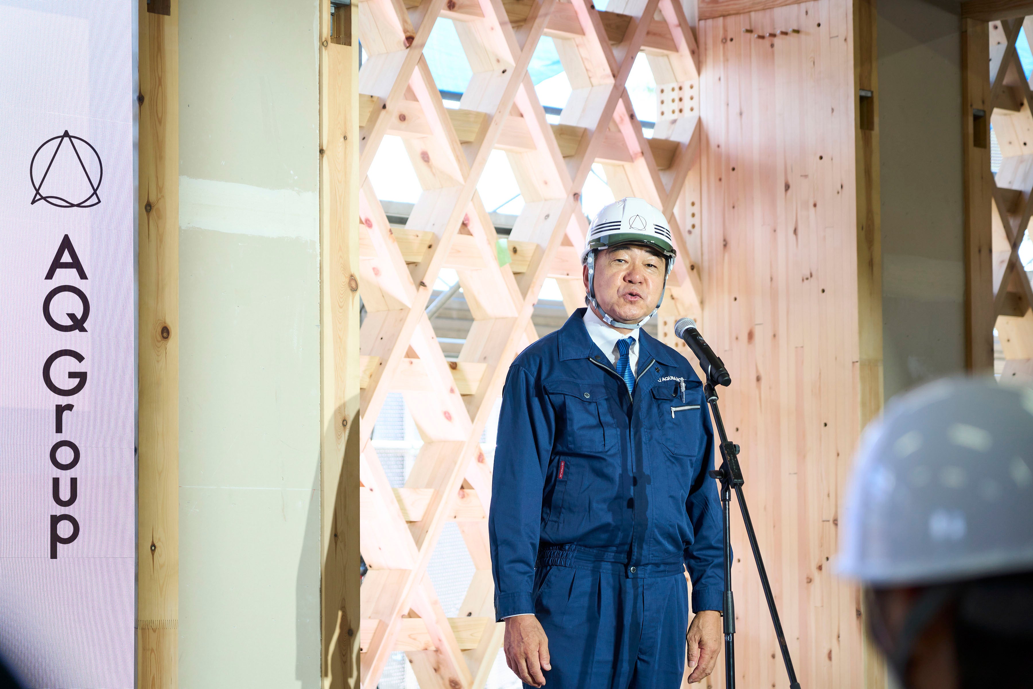 構造体でもあり意匠的でもある組子格子耐力壁の前で挨拶する代表取締役社長　宮沢俊哉