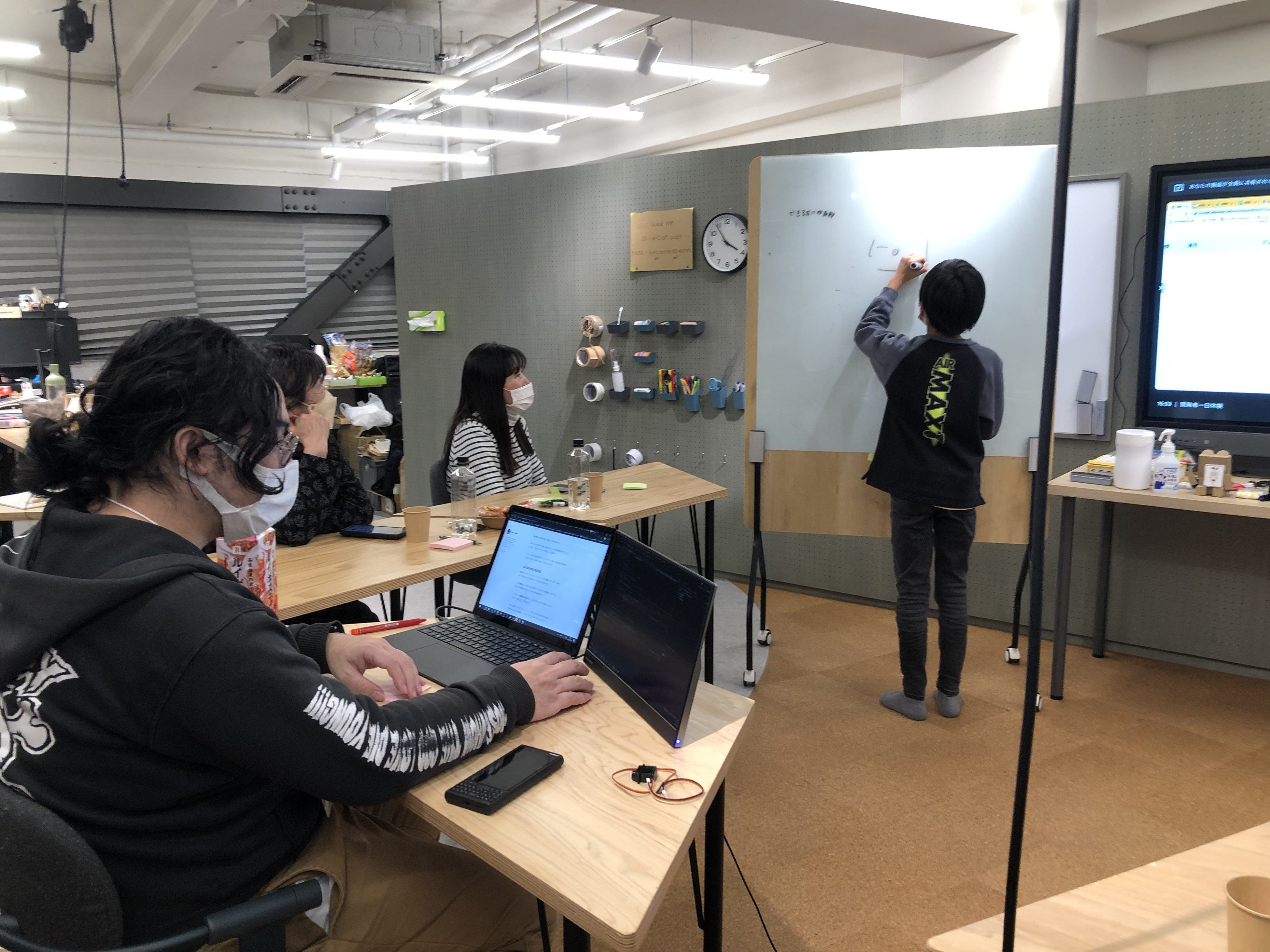 ホワイトボードにデザイン案を描く清水さん