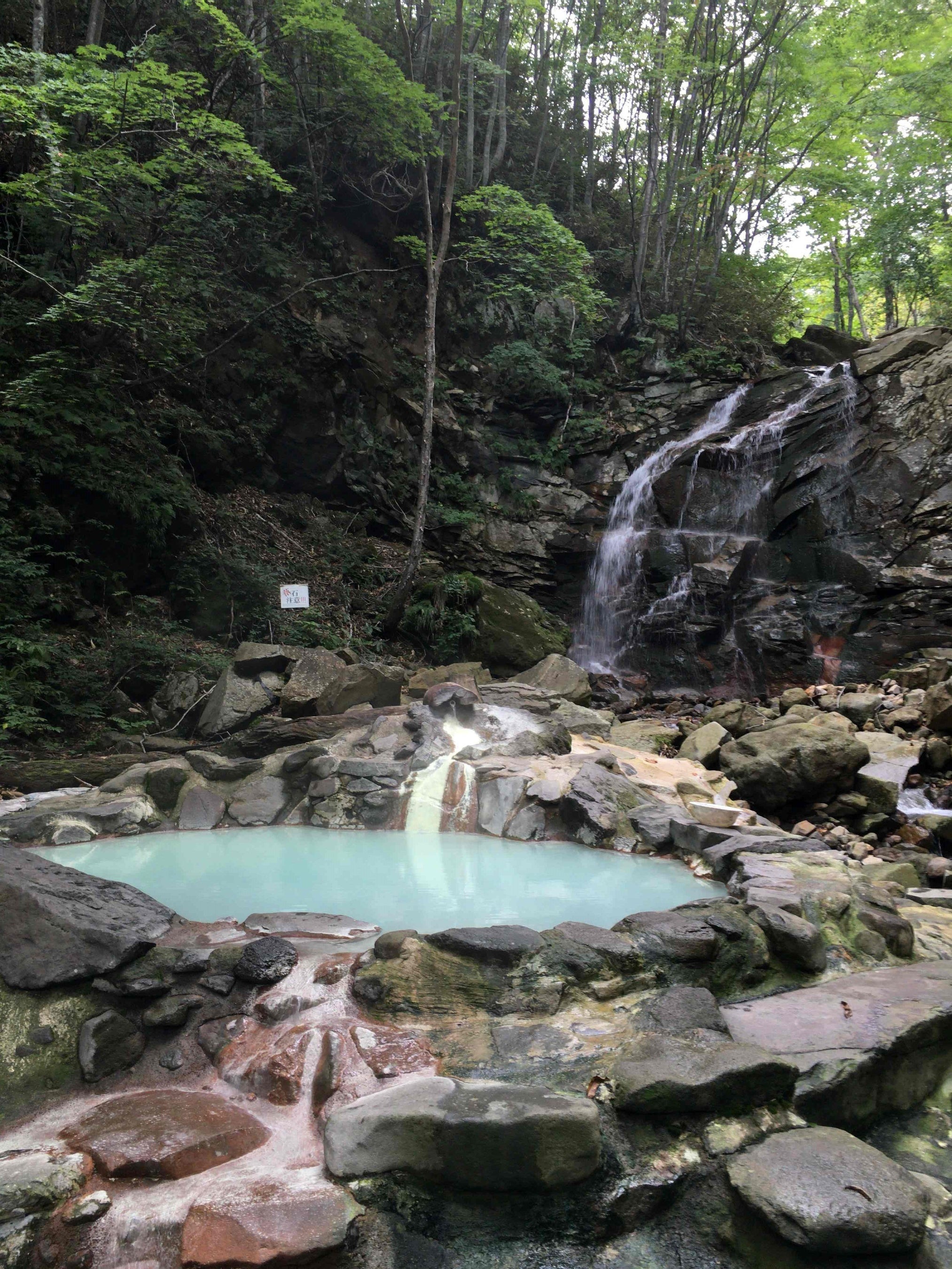 滝の流れ落ちる沢沿いにある野趣あふれる野天風呂です