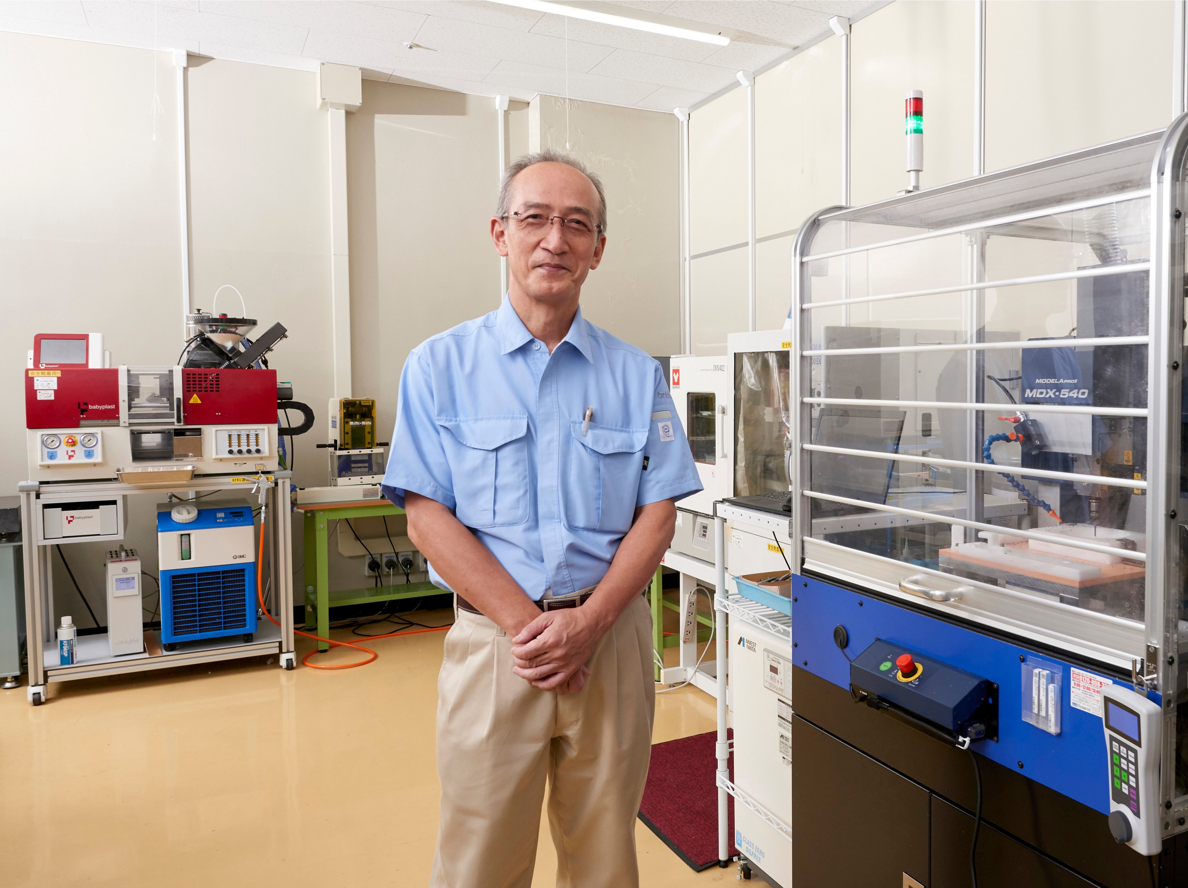 開発センター 新規事業推進部 事業開発グループ 技術士（機械部門 総合技術監理部門）　矢澤 宏明 氏と、3D造形室に設置されている「デザインファクトリー」システム