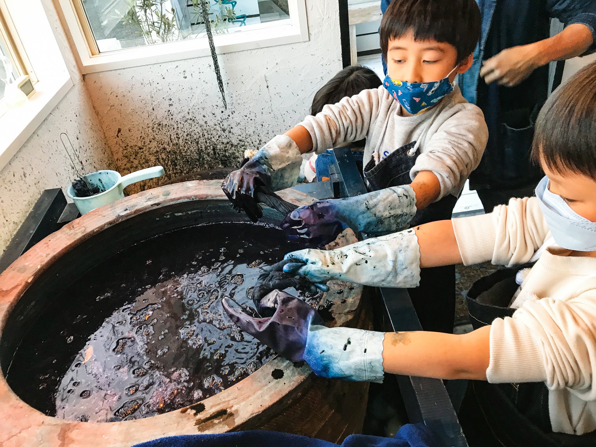 伝統的な灰汁発酵建て藍染体験をする子どもたち