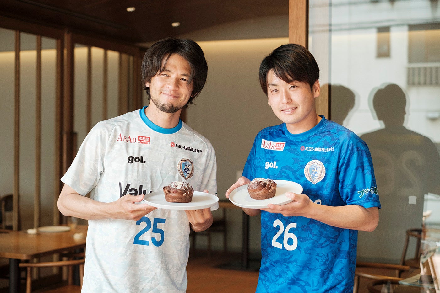 「クランベリージャムとナッツのショコラパン」と南葛SC選手、左が石井謙伍選手、右が秋山大地選手　　　　　　　　　（2022年４月、カフェ・マルガパーネでの試食会にて撮影）