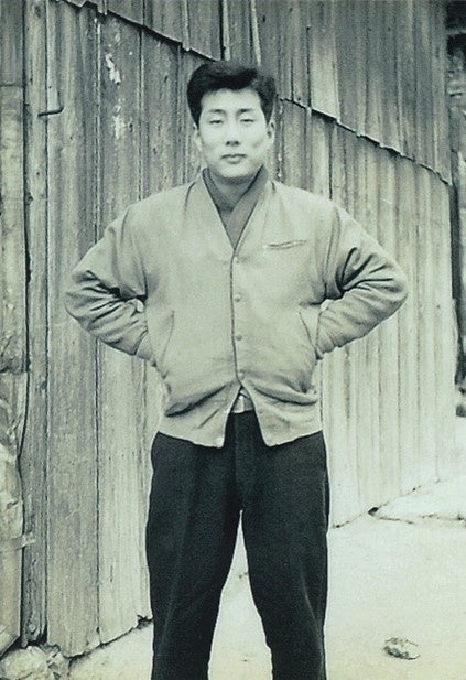  個人商店の前で立つ創業者 角谷勝司