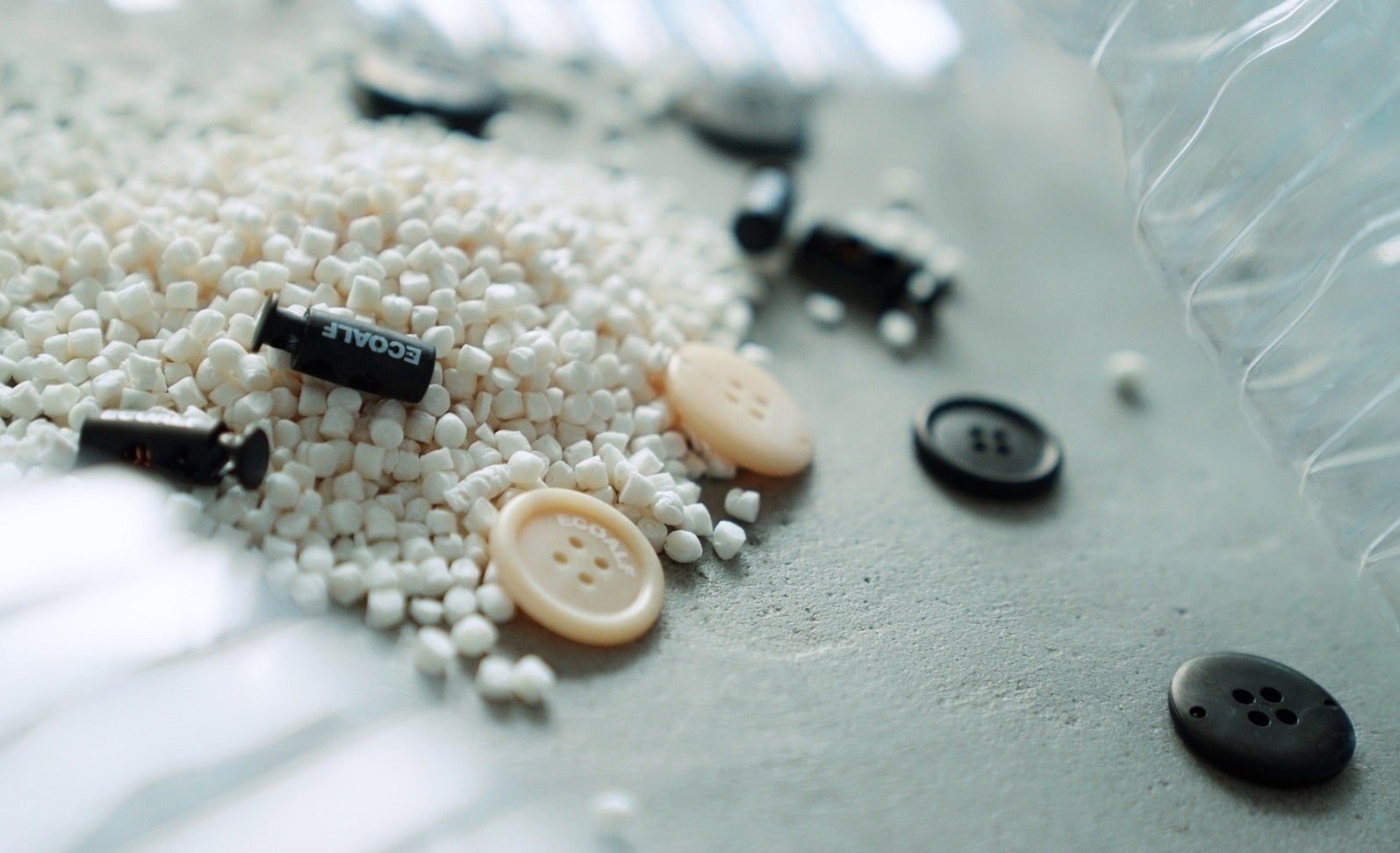 パナソニックと共同開発した環境負荷の低い材料による 釦とスピンドルストッパー（白い粒はkinariのペレット）