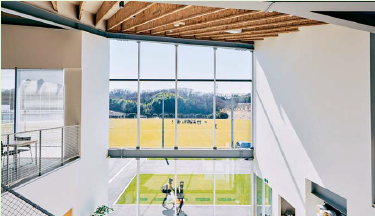 目の前のグラウンドへと視線を通す 吹き抜けのエントランス