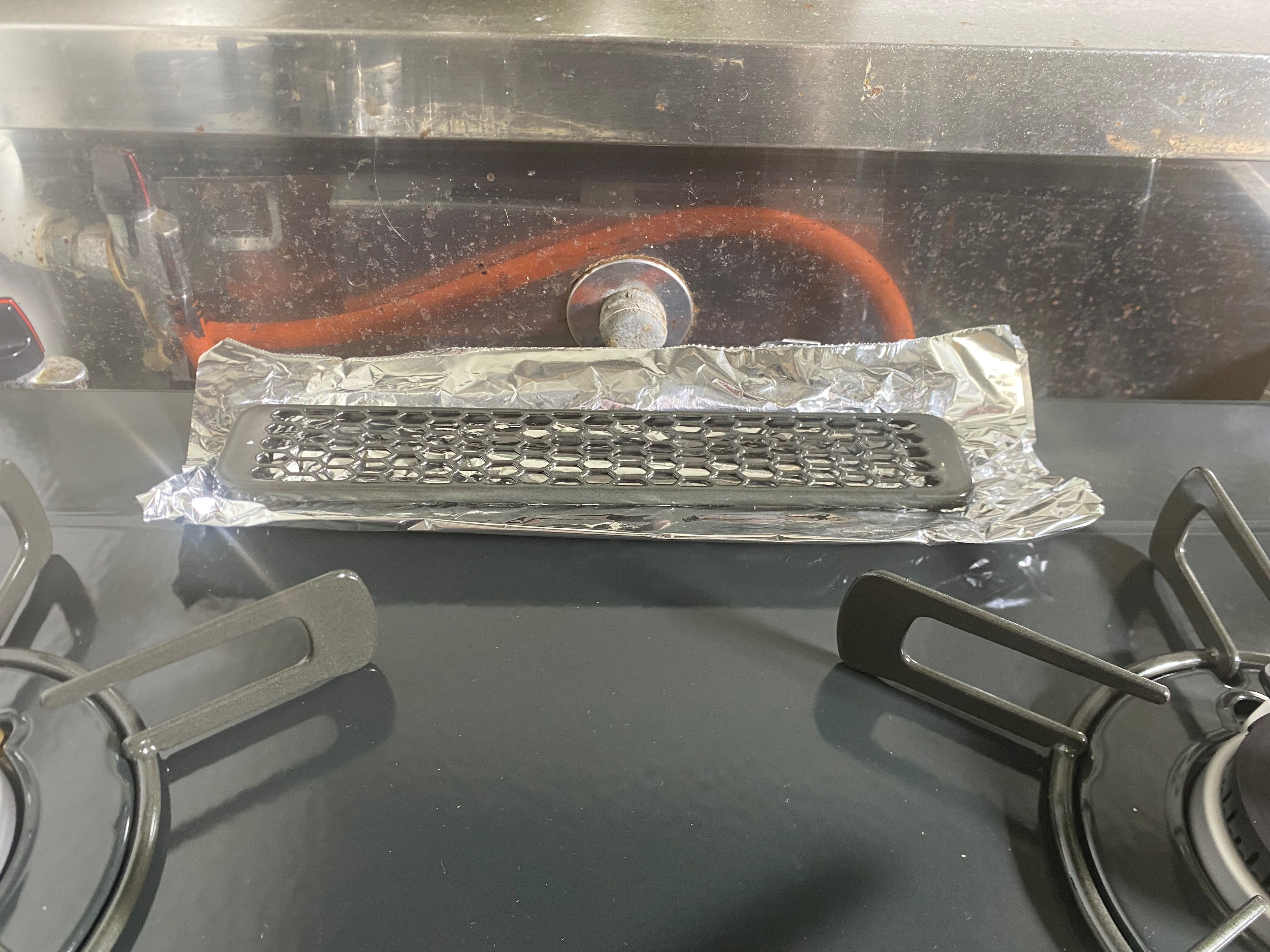 グリル排気口をアルミ箔でふさぐ様子