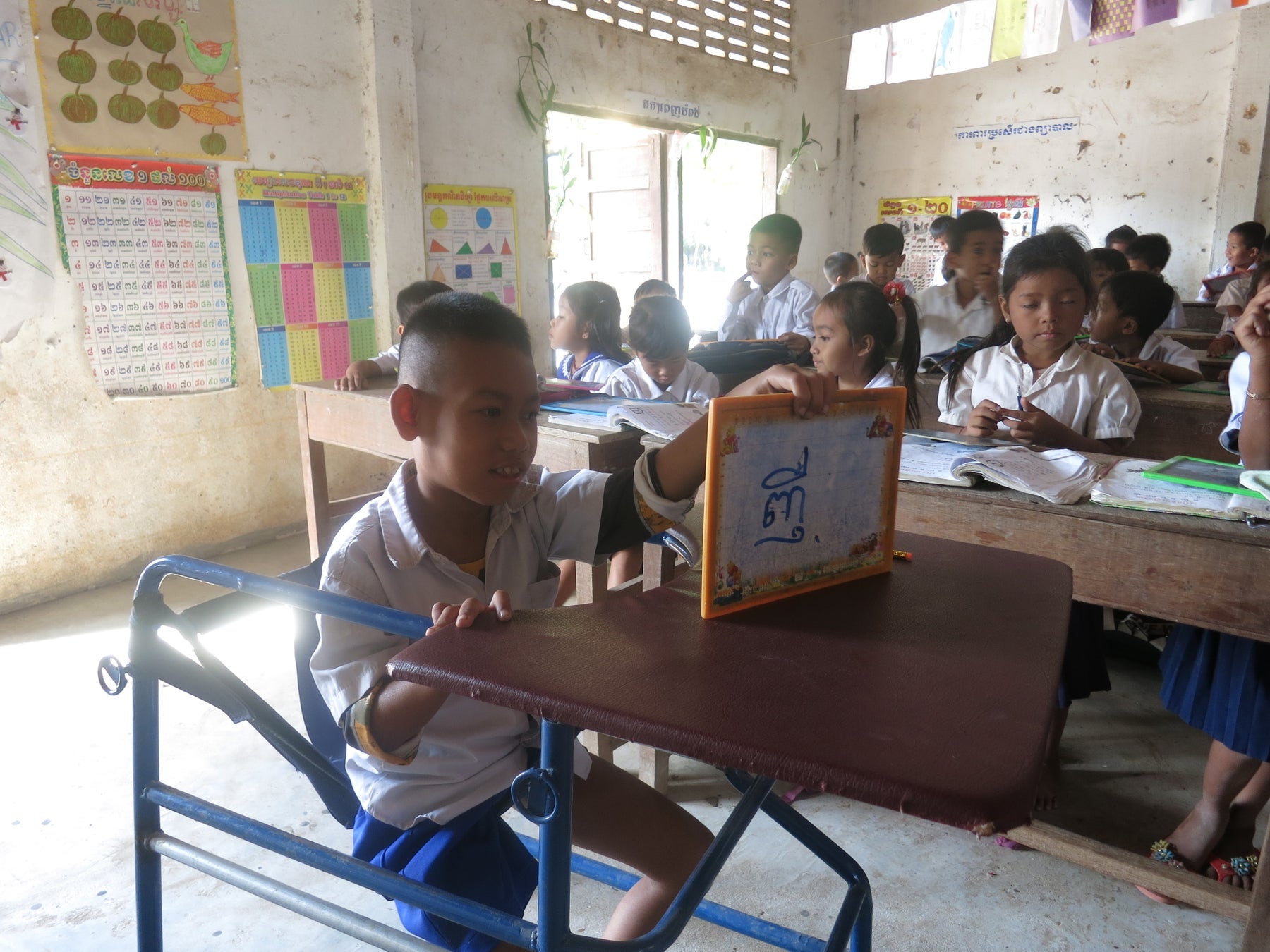 教員や同級生からの声がけや移動時の支援など、適切な配慮を受けて授業に参加する児童(カンボジア・カンダール州)