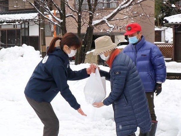 ドローン配送された「ごはんセット」を スタッフから受取る前川さんご夫妻