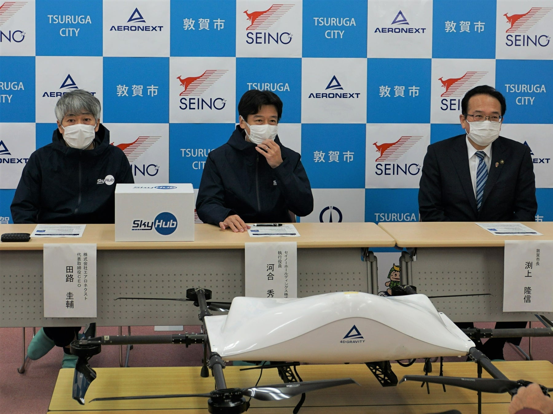 実証実験の背景や概要を説明する写真向かって 右より敦賀市長渕上隆信、セイノーHD執行役員 河合秀治、エアロネクスト代表取締役CEO田路圭輔