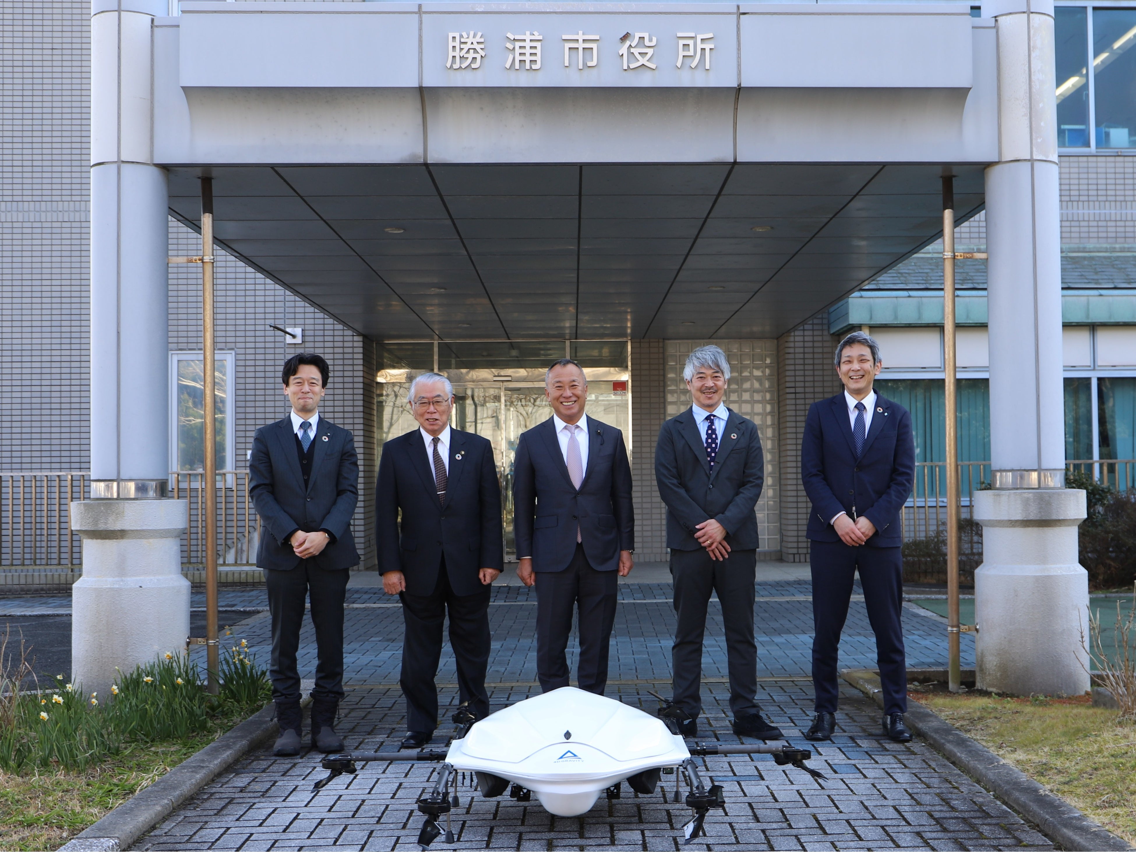 エアロネクストの物流専用ドローンを前に、 向かって左よりセイノーHD執行役員 河合秀治、勝浦市長土屋元、勝浦商工会長小髙伸太、エアロネクスト代表取締役CEO田路圭輔、住友商事 航空事業開発部長多々良一郎