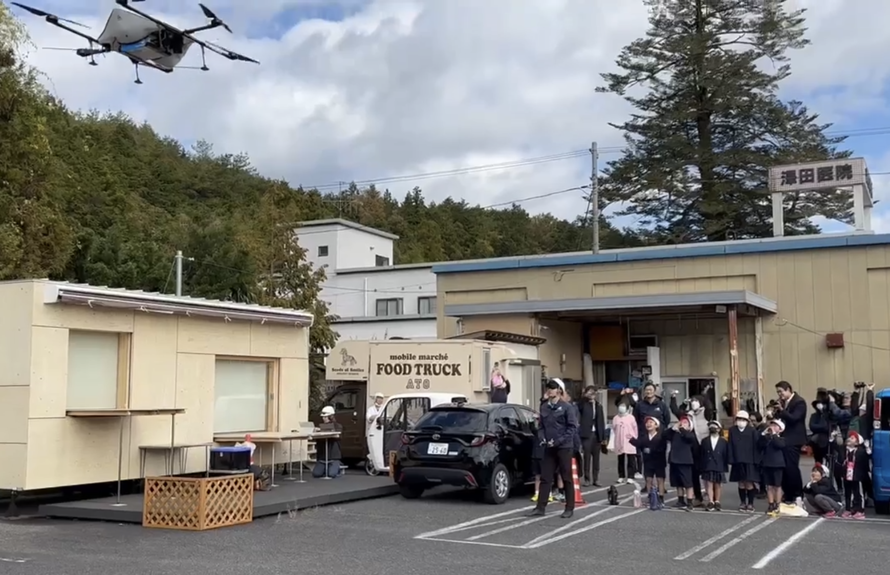 寄書を搭載した物流専用ドローン”AirTruck”の離陸を見守るさくら小学校の児童 （ほほえみの郷トイトイ駐車場）