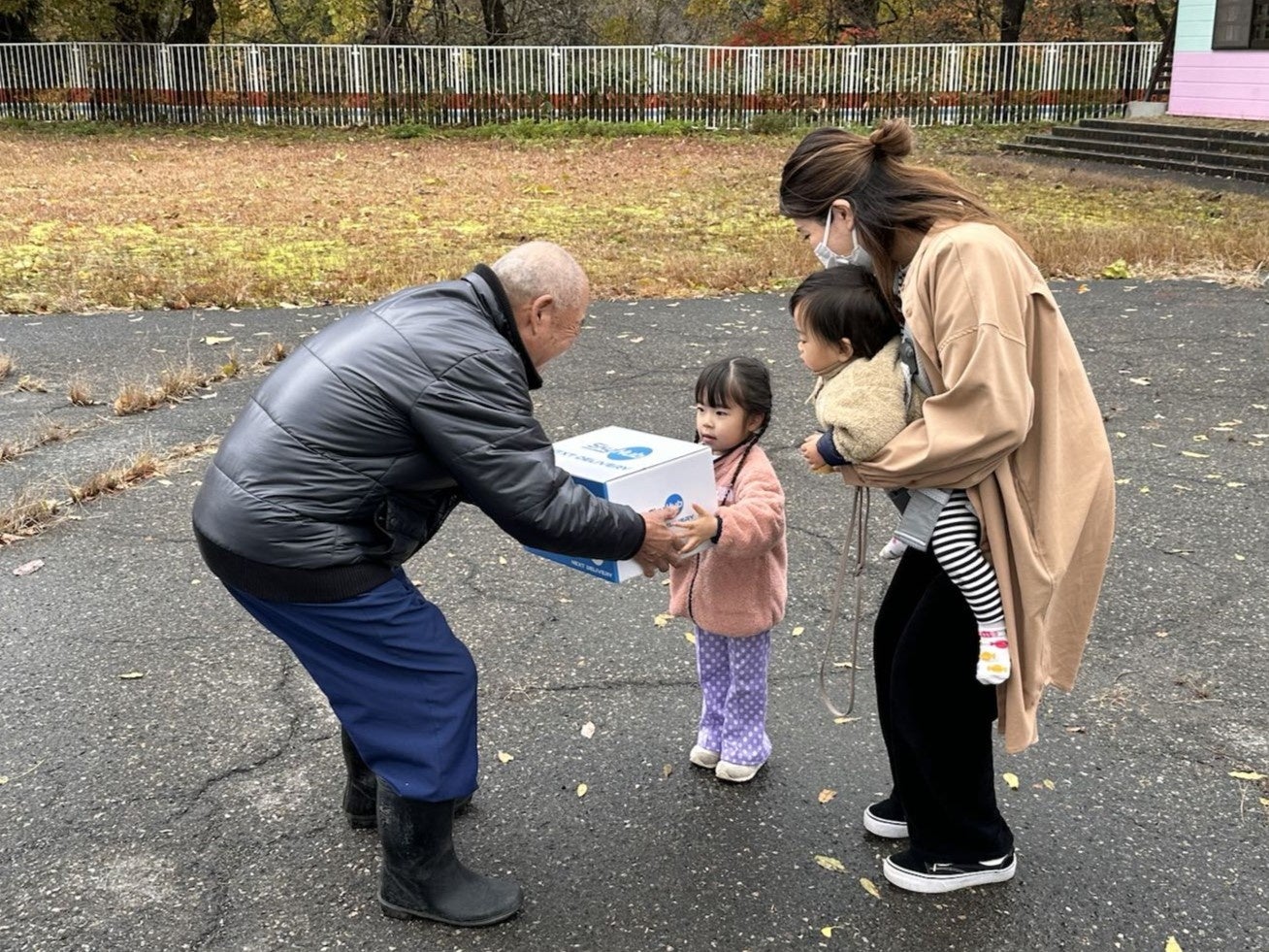 ドローンで届いたお蕎麦の入った箱を受け取る住民 （旧日野川保育園）