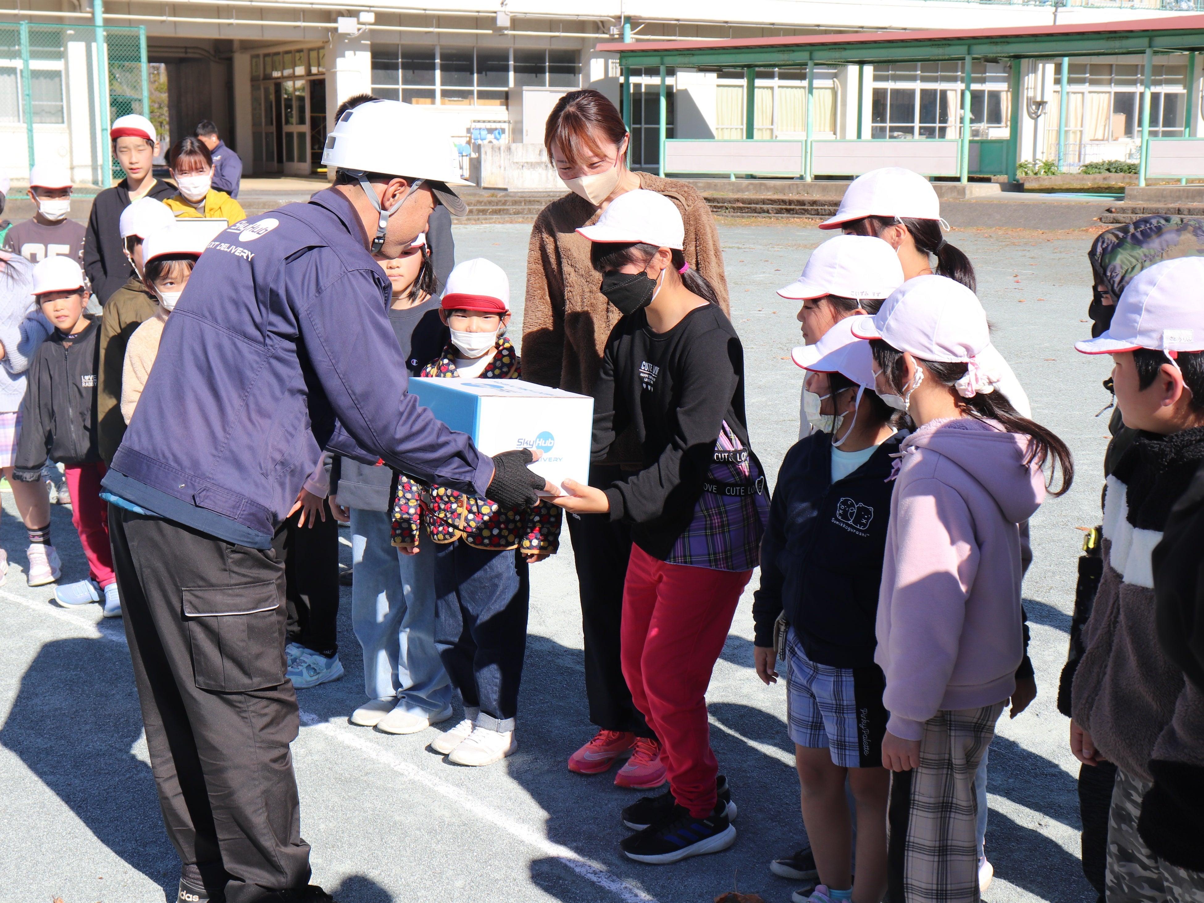 ドローン配送されたお菓子を受け取る川根小学校の生徒たち （本川根小学校グラウンド）