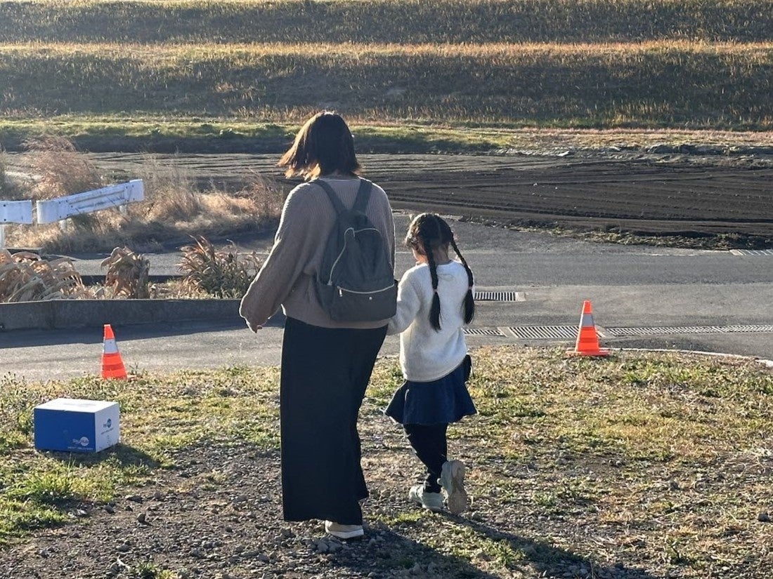 ドローンで置き配された荷物を取りに行く住民の親子