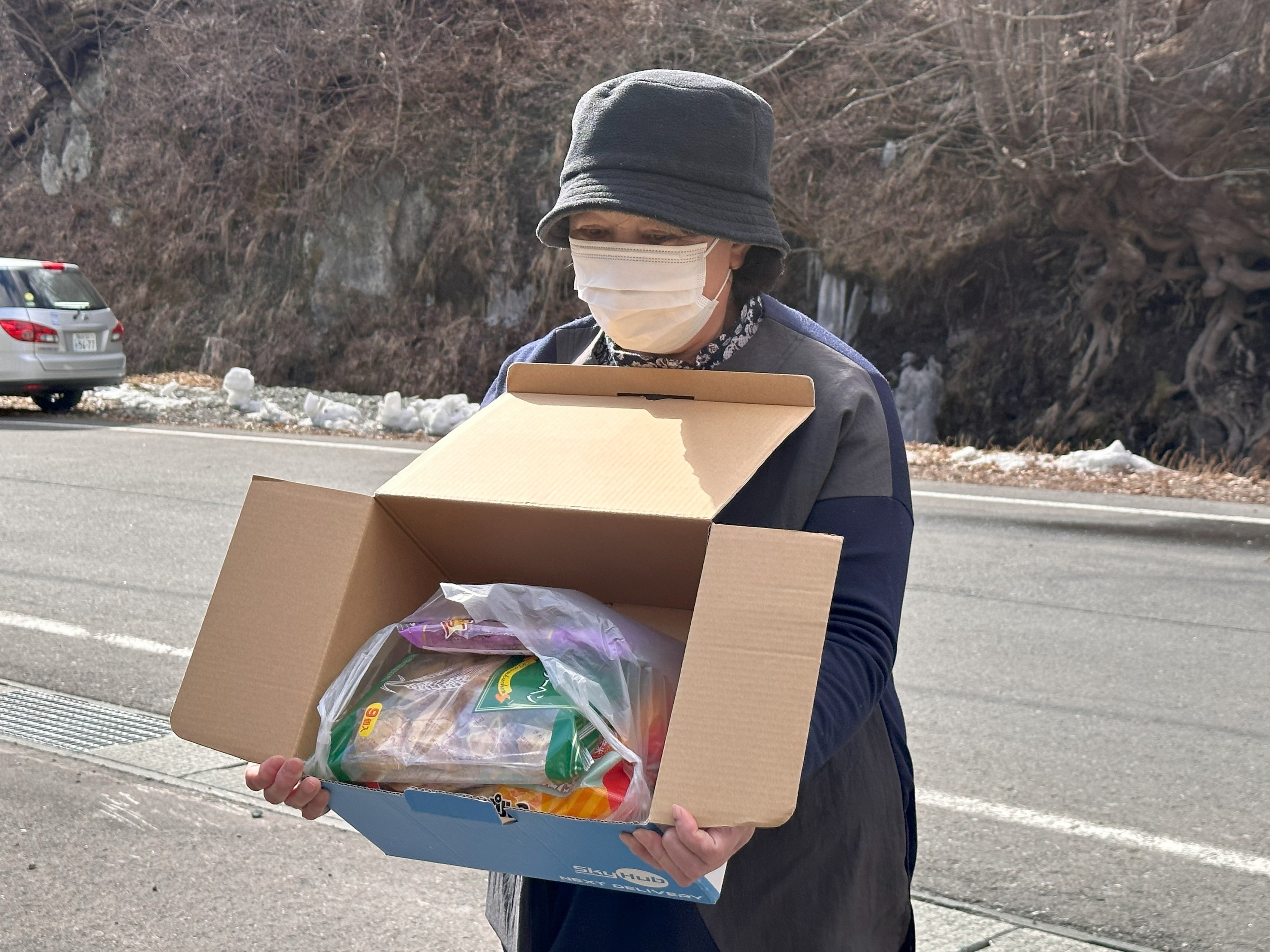 ドローン配送されたお菓子とドリンクを受け取った後藤和子さん