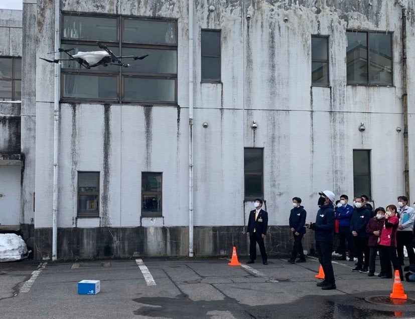 鹿瀬診療所に処方薬（模擬）を届けて飛び去るＡＣＳＬとエアロネクストの物流専用ドローン（阿賀町鹿瀬地区）