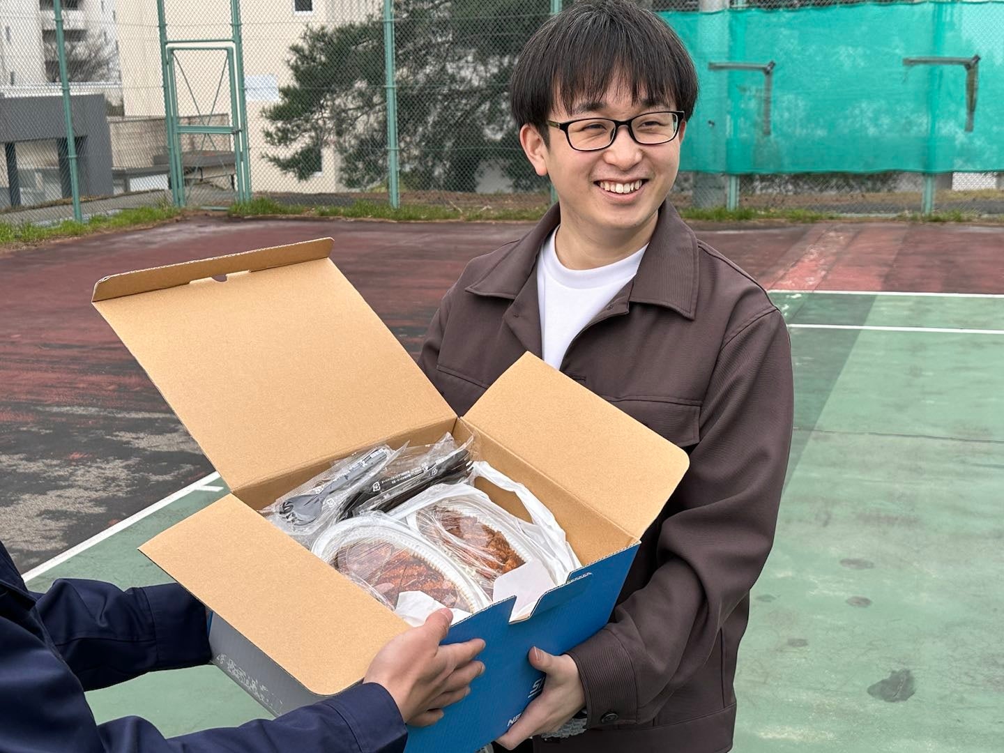 ドローン配送されたチャンピオンカレーを受け取る大学の学生さん （北陸先端科学技術大学院大学）