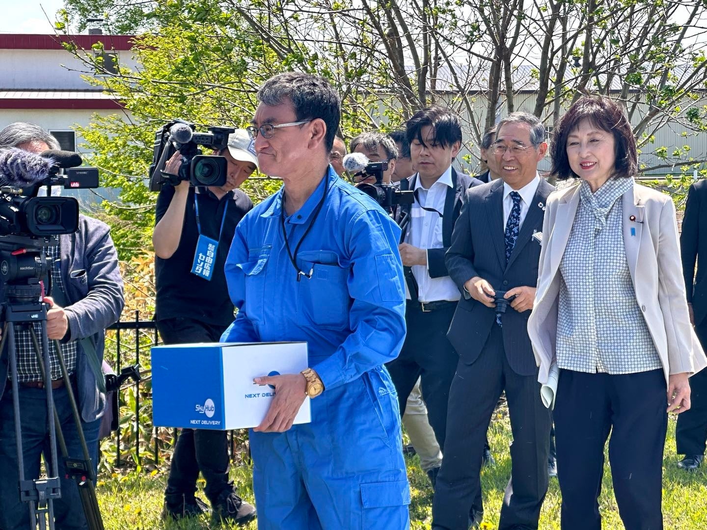 物流専用ドローンAirTruckから置き配されたかみしほろイーツ(tobachi)のお弁当を受け取る河野デジタル大臣 （かみしほろシェアオフィス）