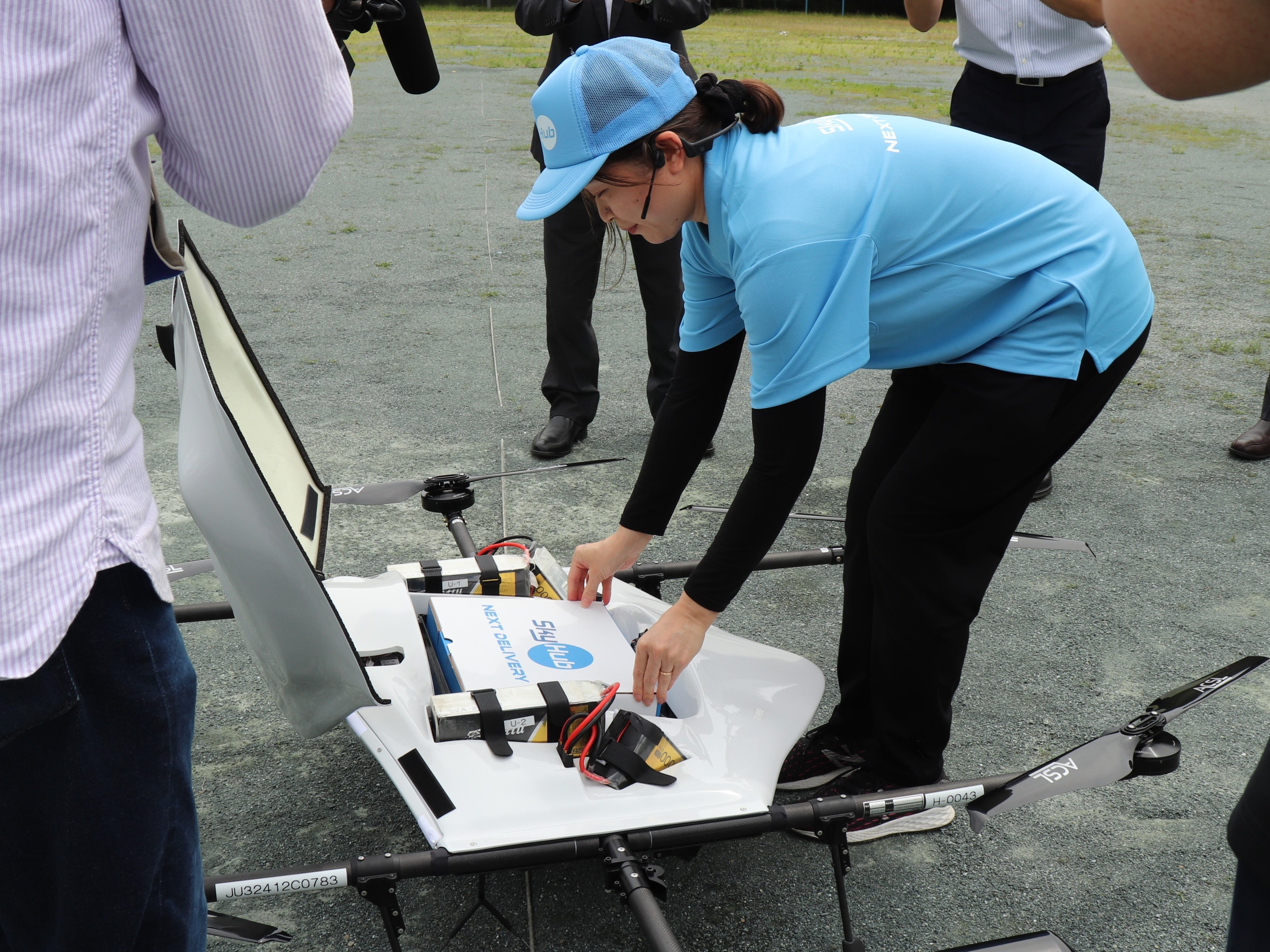 物流専用ドローンAirTruckに食料品の入った専用箱を取り付けるスタッフ （離陸地点の旧中川根南部小学校グラウンド）