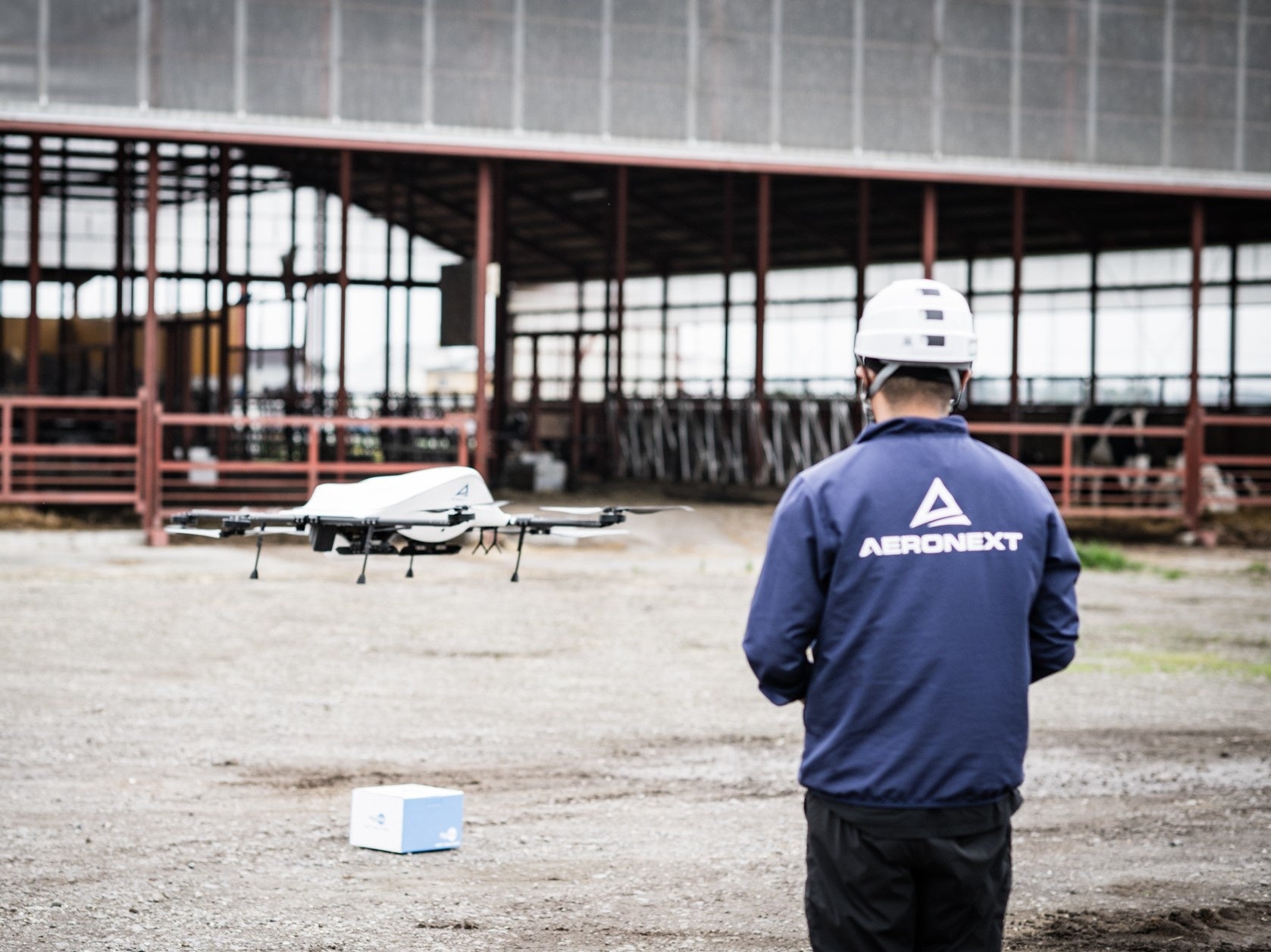 受精卵が入った箱を届けて飛び去る ドローン（熊谷牧場牛舎前）