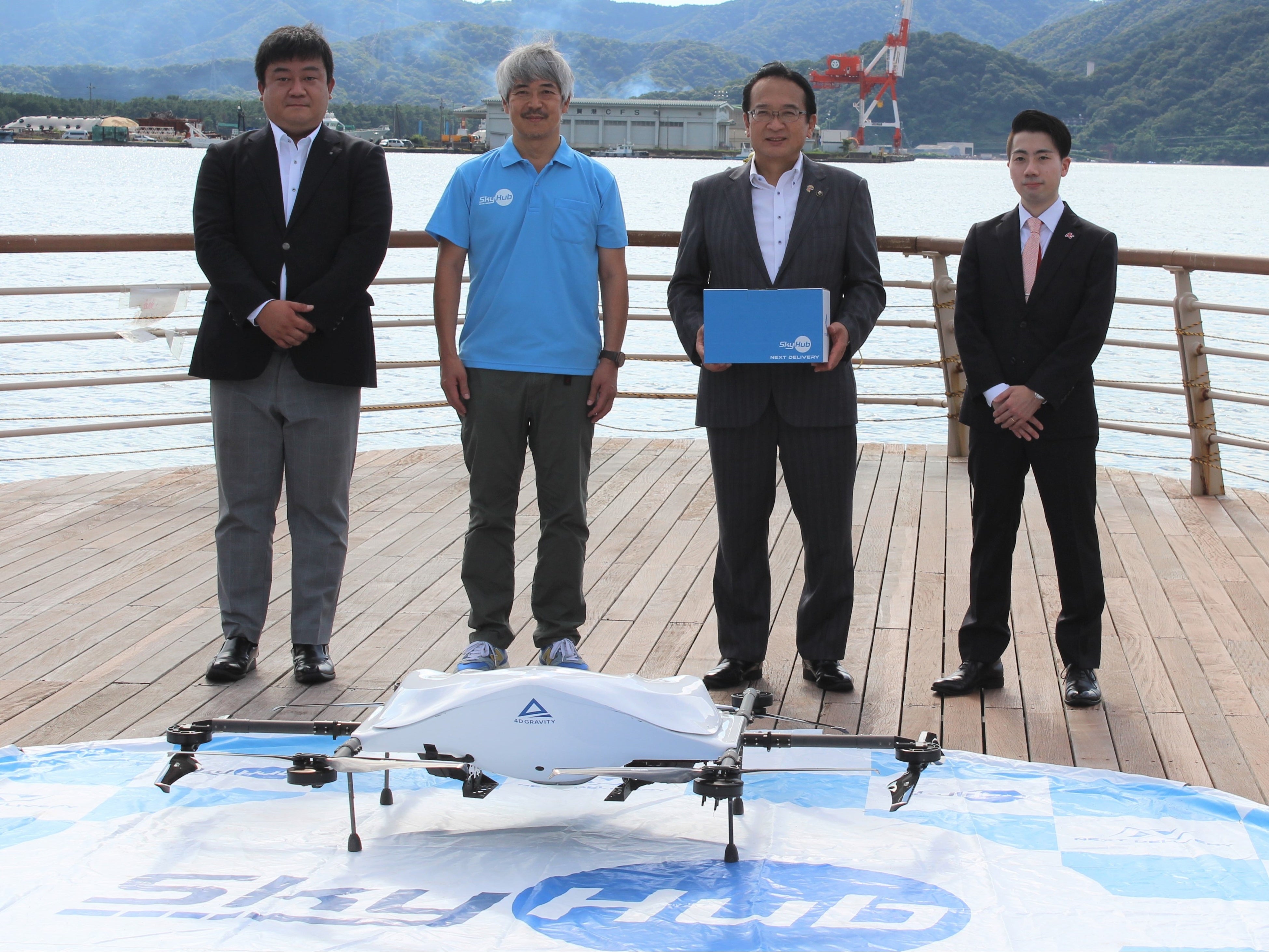 使用したドローンを前に写真向かって左よりセイノーHD事業推進部ラストワンマイル推進チーム課長和田悟、NEXTDELIVERY代表取締役田路圭輔、敦賀市長渕上隆信、出前館シェアリングデリバリー本部長執行役員森山海太
