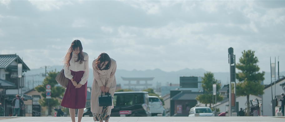 出雲路に到着した女性2人。 これから始まる旅に わくわくする女性の表情。 出雲大社の鳥居の前で 立ち止まり笑顔