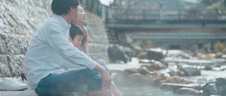 玉造温泉を流れる 玉湯川のほとりで 足湯を楽しむ家族。ゆったりと流れる時間に 満足そうな母親の笑顔。