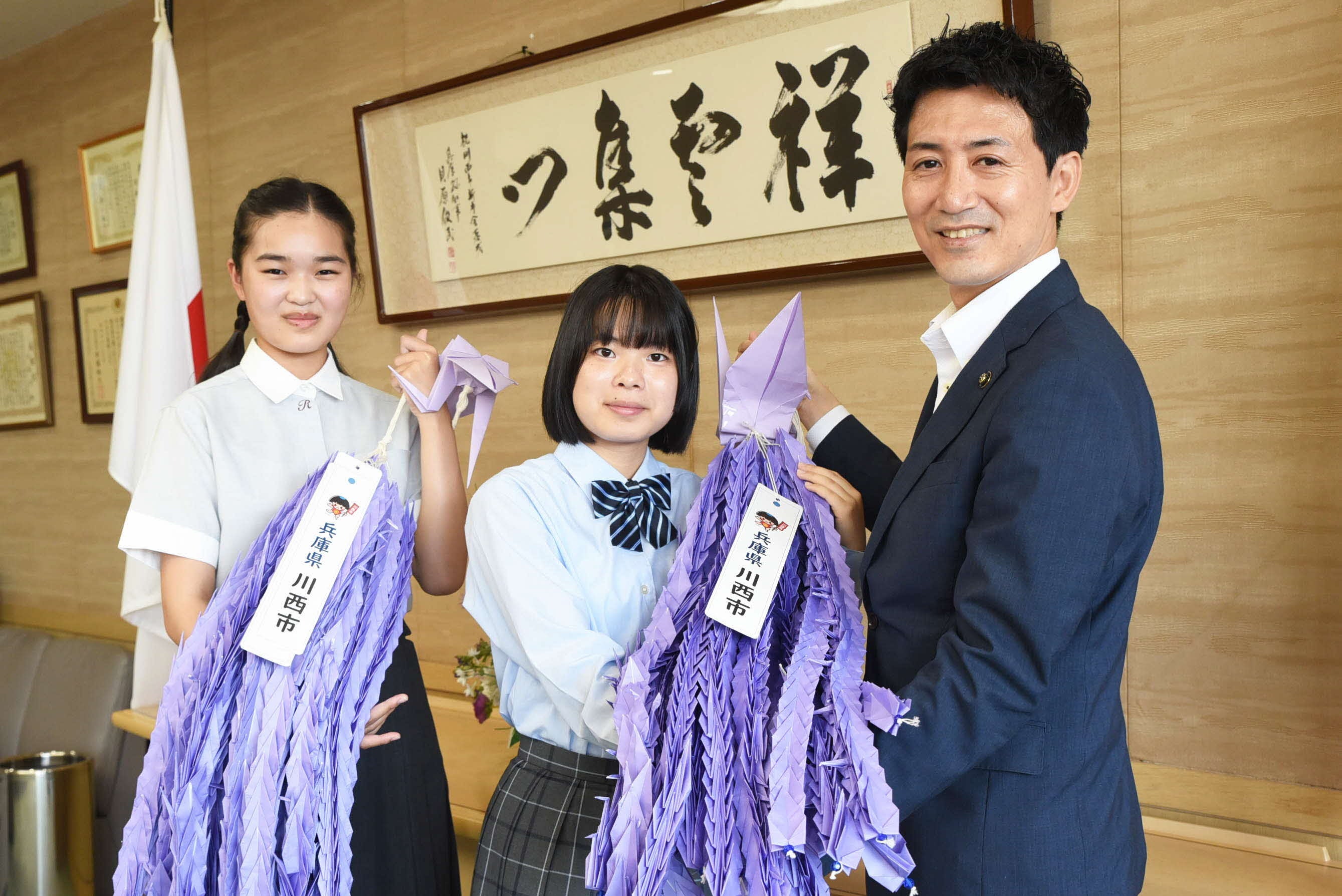 越田市長から折り鶴を託される折り鶴平和大使の２人。小室さん（写真右）、出野さん（写真左）