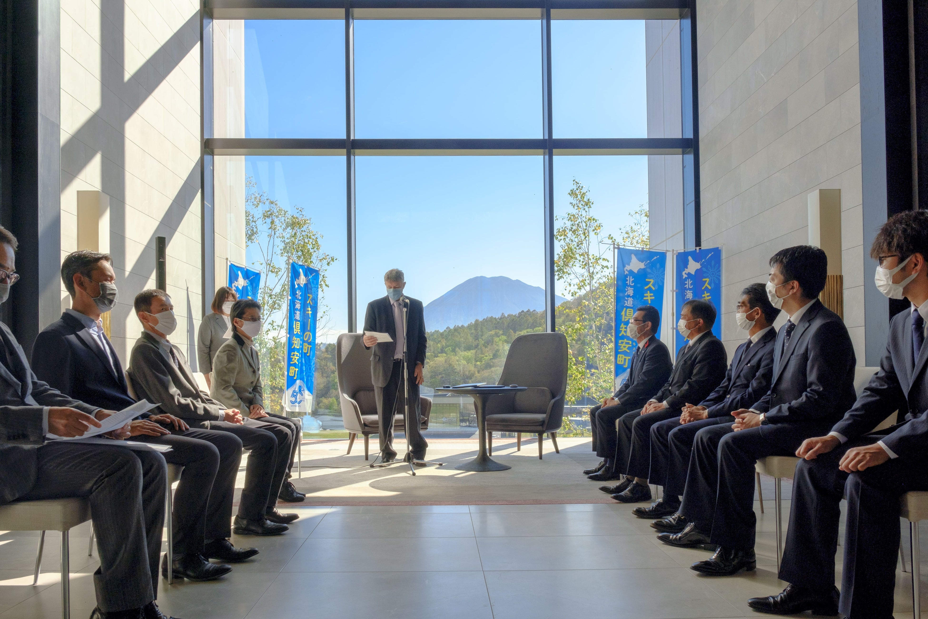 ニセコHANAZONOリゾートをバックにスピーチするコリン