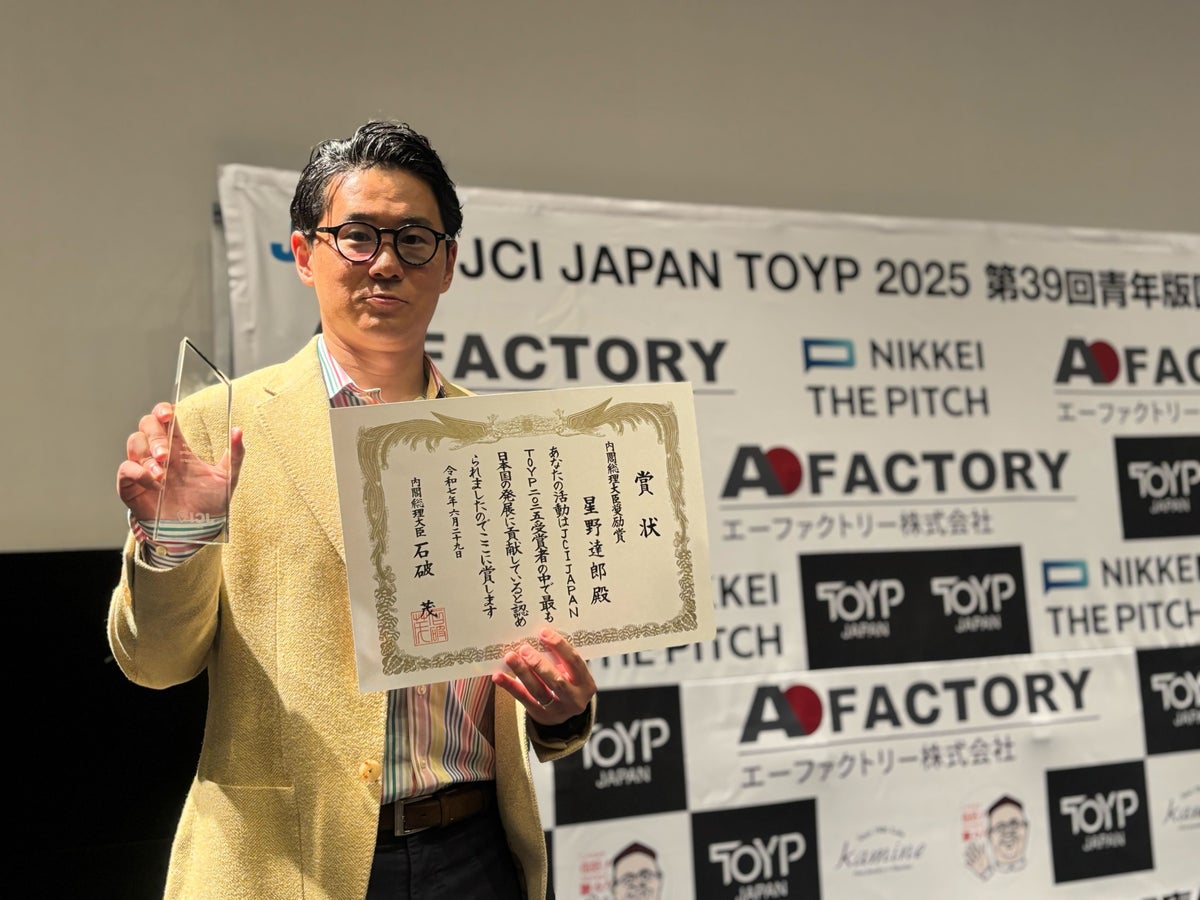 青年版国民栄誉賞の賞状と表彰盾とともに記念撮影する星野達郎