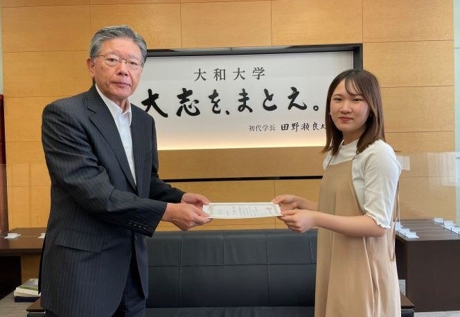 「ミャクミャク」の愛称決定の功績を称え田野瀬学長より表彰を受ける作田さん（2022年9月）